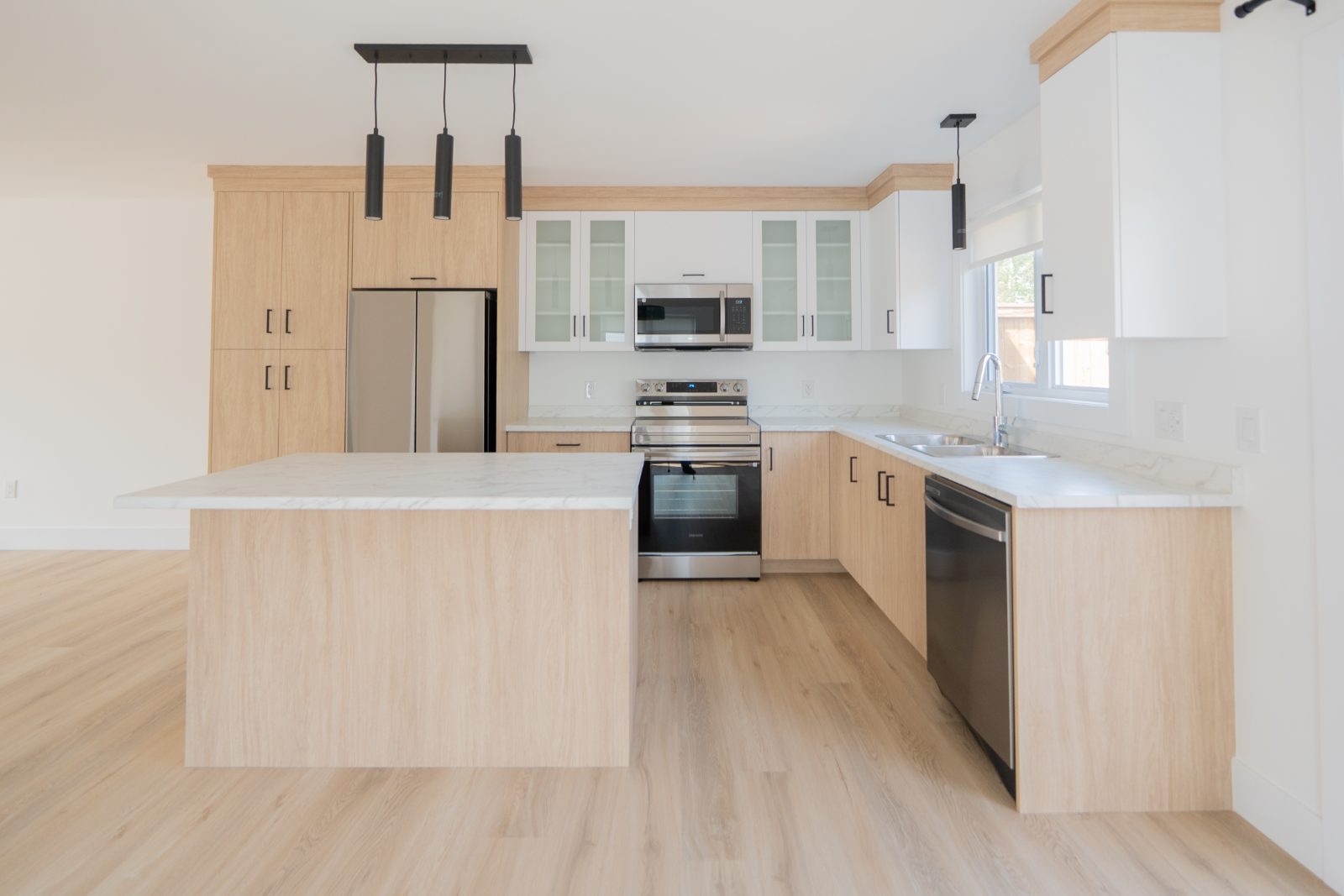 Move-in ready kitchen with island, light wood cabinetry and stainless appliances